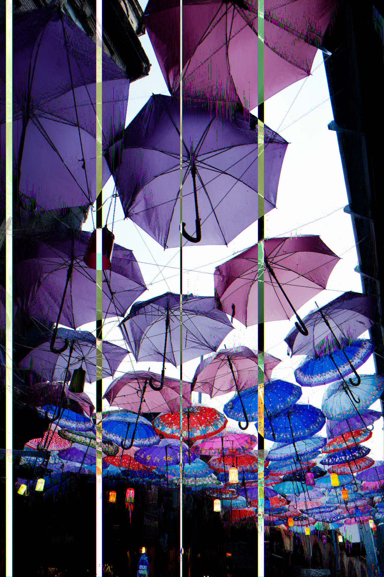 A glitched photo of umbrellas over a street.
